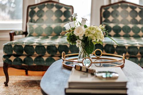 un jarrón de flores en una mesa con dos sillas en The Historic Berkeley Place en Staunton