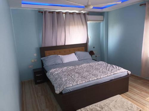 - une chambre dotée d'un lit avec un mur bleu dans l'établissement Sarah apartment B4R, à Ogbojo