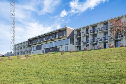 an apartment building with a grassy hill in front of it at The Jordan Hotel Ramada by Wyndham in Jordan
