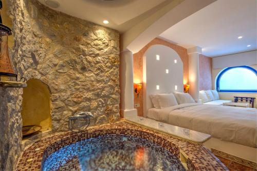 a bedroom with a large tub in a stone wall at Astarte Suites in Akrotiri