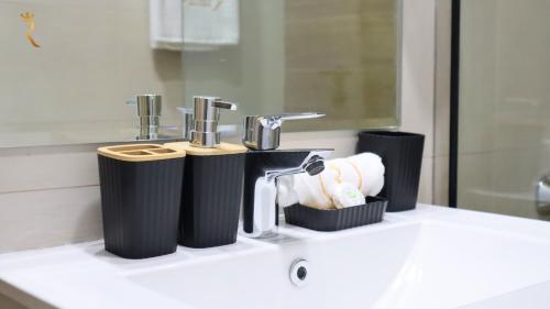 een badkamer met een wastafel met 2 kranen en handdoeken bij Aurora Your 2BR Duplex Transit Apartment in Abu Dhabi