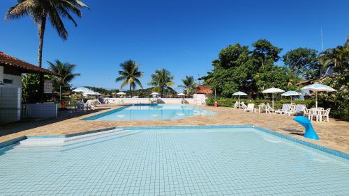 una piscina en un complejo turístico con sillas y sombrillas en Apartamentos, 3 Praias, condomínio de Luxo, Piscinas, en Angra dos Reis