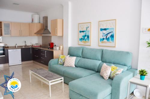 ein Wohnzimmer mit einer blauen Couch und einer Küche in der Unterkunft Kos Apartment - Elodie Paradise in Mogán