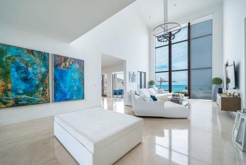 The Bahamas Beachfront Dream Villa في أليس تاون: غرفة معيشة بها أريكة بيضاء و لوحة