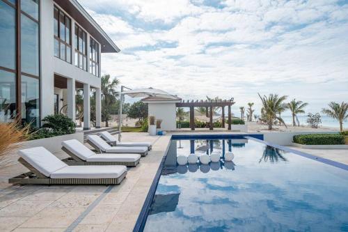 The Bahamas Beachfront Dream Villa في أليس تاون: مسبح مع كراسي جلوس بجانب مبنى