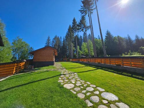 a grassy yard with a fence and a stone pathway at Pensiunea Ana Maria Durau in Durau