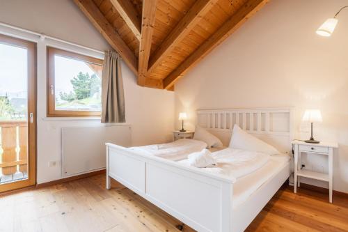 Cama blanca en habitación con ventana en Haus Ahornweg en Bad Kleinkirchheim