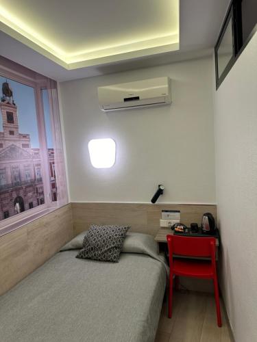 a bedroom with a bed and a red chair at Hostal Castilla II Puerta del Sol in Madrid
