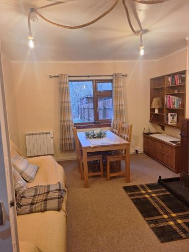 a living room with a wooden table and a window at Twin Deer Lodge in Glenfinnan