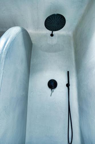 a shower in a white wall with a shower head at La Ponta Villas & Suites in Akrotiri
