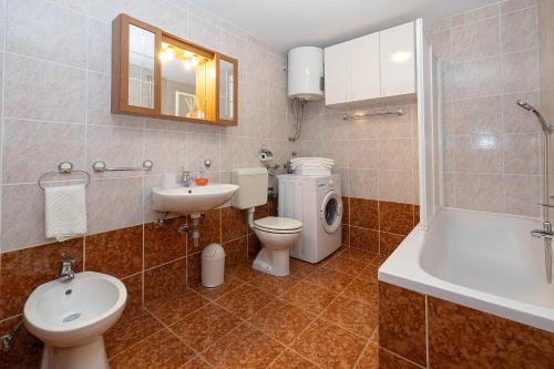 a bathroom with a toilet and a sink and a tub at Apartments Casa Mia in Dramalj