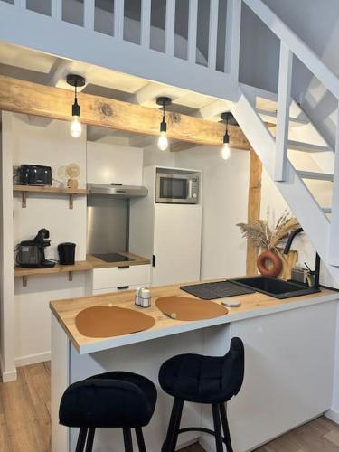 - une cuisine avec deux tabourets à un comptoir et un évier dans l'établissement Duplex lumineux, à Nantes