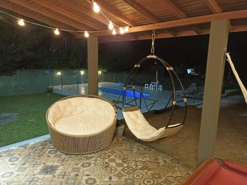 un columpio en un pabellón con piscina por la noche en Encantos do Rosa, en Praia do Rosa