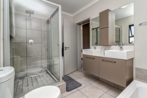 a bathroom with a shower and a toilet and a sink at Modern Fourways 3-Bed Loft - Backup Power in Sandton