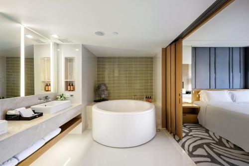 a bathroom with a large tub and a bed at Centara Grand at Central Plaza Ladprao Bangkok in Bangkok