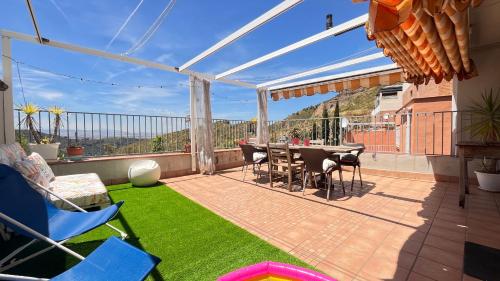 un patio con mesa, sillas y césped en CASA LOS ABETOS cerca de la Alhambra y Sierra Nevada, en Cenes de la Vega