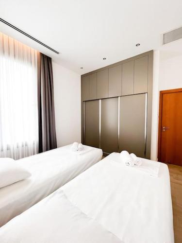 two white beds in a room with a window at Dreamview Suite Beachfront Getaway in Mağusa