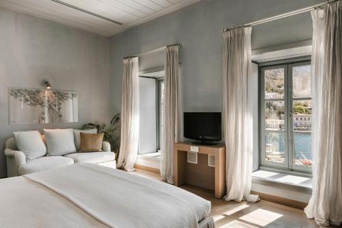 a bedroom with a bed and a tv and windows at Hydrea Exclusive Hospitality in Hydra