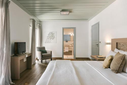 a white bedroom with a bed and a television at Hydrea Exclusive Hospitality in Hydra