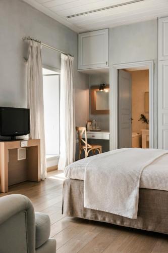 a bedroom with a bed and a television and a chair at Hydrea Exclusive Hospitality in Hydra