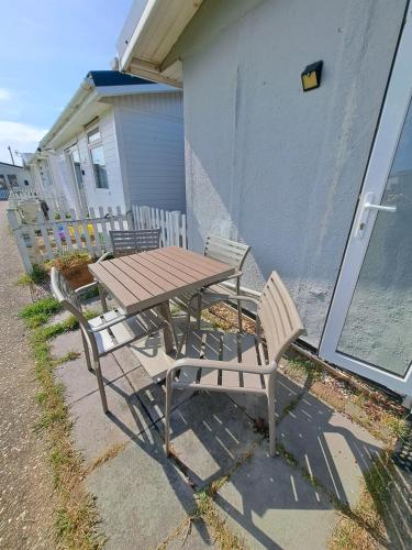 a picnic table and two chairs next to a building at Beside the Sea Chalet, Mablethorpe in Mablethorpe