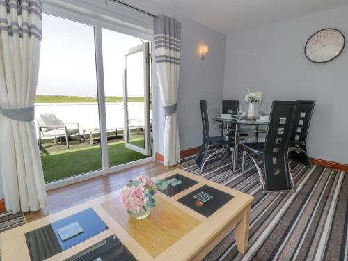 a living room with a table and a large window at Sea Breeze in Caernarfon