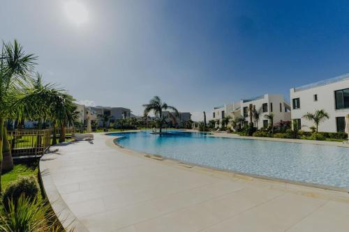 a large swimming pool with palm trees and buildings at Peaceful Suite Beachfront Getaway in Mağusa
