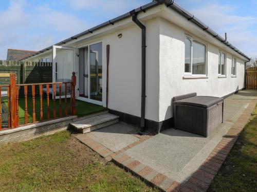 a small white house with a bench on a patio at Sea Breeze in Caernarfon