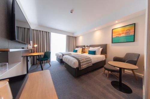 a hotel room with a bed and a table and chairs at Holiday Inn Blackpool by IHG in Blackpool