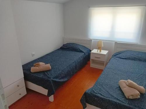 two beds in a bedroom with blue sheets and towels at Voula's maisonette in Acharavi