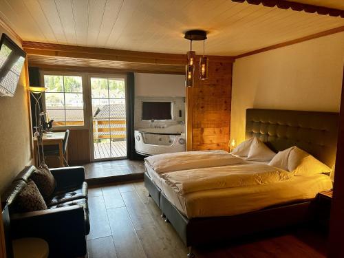 a bedroom with a large bed and a balcony at Chalet Hotel Adler AG in Kandersteg