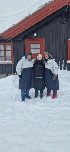 tres personas de pie en la nieve frente a un edificio en Skotten Seter - Bed & Husky en Mork