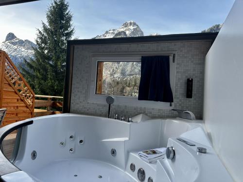a white bath tub in a room with mountains at Chalet Hotel Adler in Kandersteg