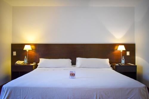 a bedroom with a large white bed with two lamps at Hotel Casino Catamarca in San Fernando del Valle de Catamarca