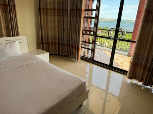 een slaapkamer met een bed en een groot raam bij Marina Lake View Apartments,Jinja in Jinja