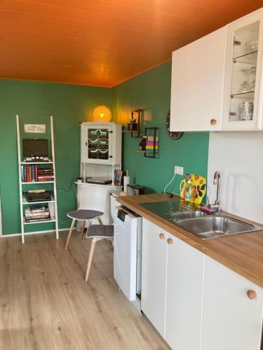- une cuisine avec des placards blancs et des murs verts dans l'établissement The Cat’s Cradle, à Grundarfjörður