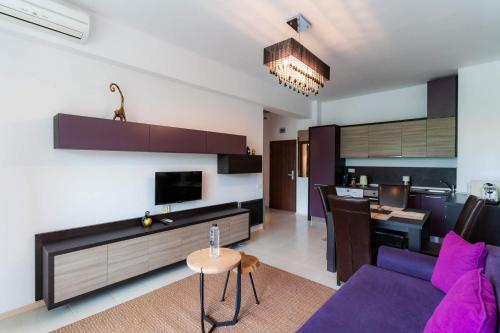 a living room with a purple couch and a kitchen at Rezident Eforie Nord in Eforie Nord