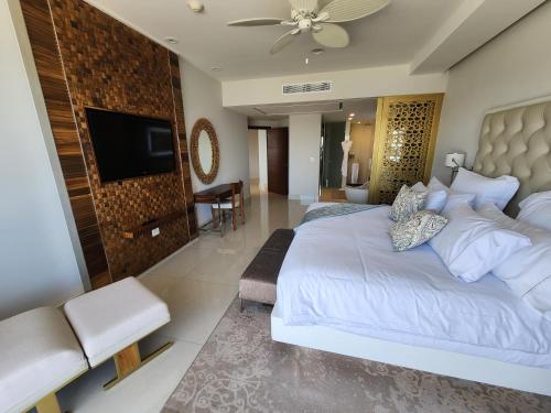 a bedroom with a large white bed and a flat screen tv at Garza Blanca Los Cabos in Cabo San Lucas