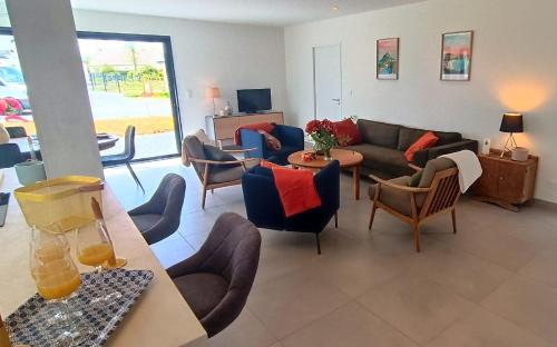 un salon avec un canapé et des chaises dans l'établissement Maison neuve proche plage avec parking gratuit et privé à 5 min du musée de la Batterie de Merville, à Gonneville-en-Auge