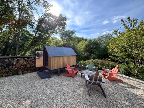 einen Hinterhof mit Spielhaus und Stühlen in der Unterkunft Cabane dans les bois vue sur ruisseau in Ploemeur