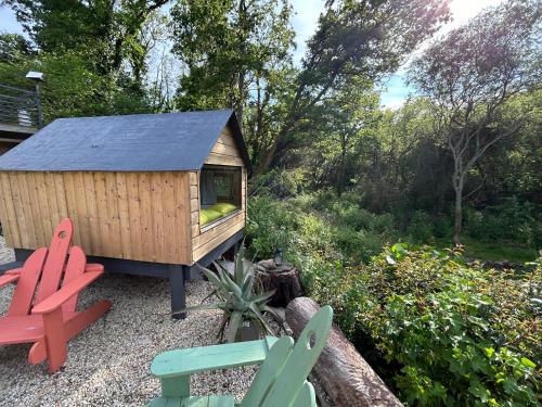 uma pequena casa de madeira com duas cadeiras num jardim em Cabane dans les bois vue sur ruisseau em Ploemeur