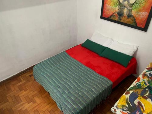 a bedroom with a bed with a red and green blanket at Savassi Hostel in Belo Horizonte
