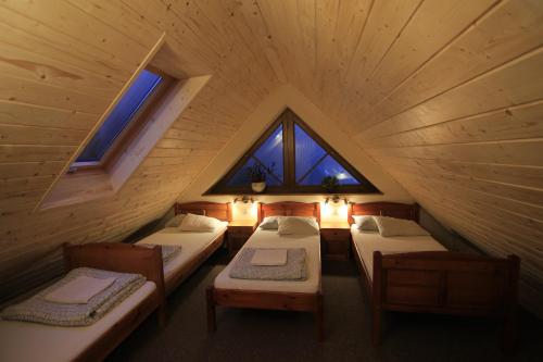 ビエルホムラ・マワにあるChata nad stawemのベッド4台と窓2つが備わる屋根裏部屋です。