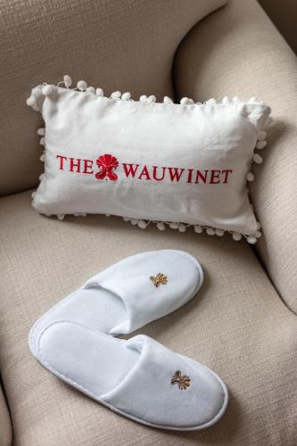 a pair of white slippers and a pillow with the wynnet at The Wauwinet Nantucket in Wauwinet