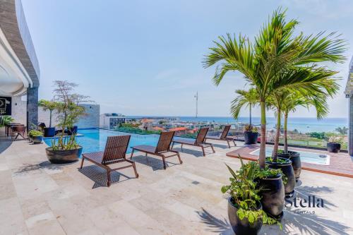 a patio with chairs and palm trees and a pool at Oceanview Infinity Pool, Steps to 5th Ave & Beach in Playa del Carmen