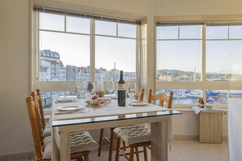ein Esszimmer mit einem Tisch und einer Flasche Wein in der Unterkunft Bleumaison-a mariña portonovo in Portonovo