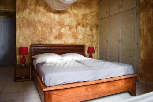 - une chambre avec un lit avec des draps blancs et 2 lampes dans l'établissement La Villa Lou, Musée Des Arts Grand Batangua, à Kribi