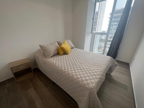 ein Bett mit zwei gelben Kissen in einem Zimmer mit Fenster in der Unterkunft Apartamento Mónaco in Guatemala