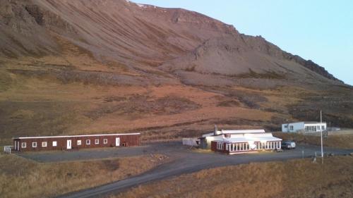 ein Gebäude auf einem Feld neben einem Berg in der Unterkunft Gil guesthouse in Búðardalur