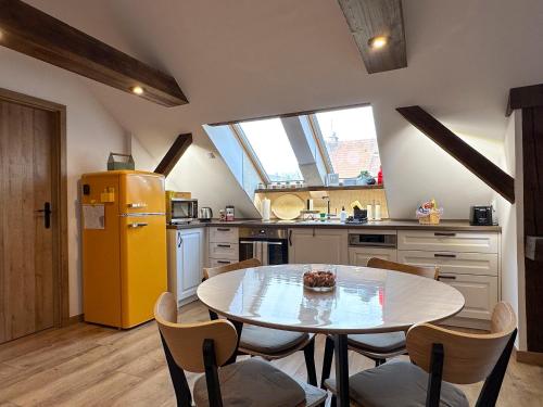 a kitchen with a table and a yellow refrigerator at MAJA Premium Loft Apartment in historical city center in Komárno